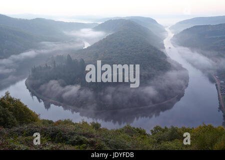 Die Saar-Schleife (Saarland, Deutschland) in der Nähe von Mettlach bei Sonnenaufgang mit Nebel und Dunst. Stockfoto