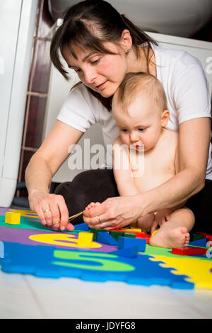 Mutter schneiden Nägel an Füßen ihres Babys - sitzen am Boden im Bad Stockfoto