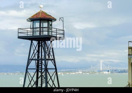 Die alte Garde Turm auf der Insel Alcatraz Gefängnis, heute ein Museum, in San Francisco, Kalifornien, USA. Blick auf den Wachturm und die neue Bay Bridge verbindet downtown San Francisco mit Schatzinsel. Stockfoto