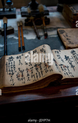 Traditionelle Schriftsteller Schreibtisch mit ein aufgeschlagenes Buch mit chinesischen Pinsel und Tinte schreiben, Shikumen Open House Museum, Xintiandi, Shanghai, China Stockfoto