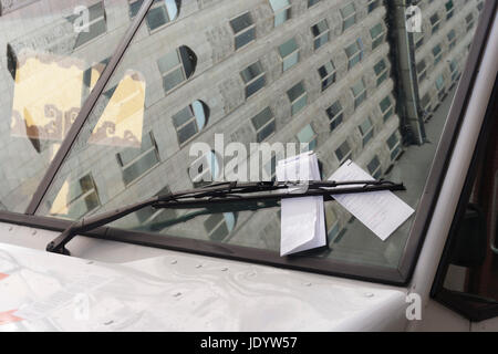 Oh, oh... Parktickets versteckt unter Scheibenwischer. Reflexion der Gebäude im Hintergrund. Niemand. Horizontale. Stockfoto