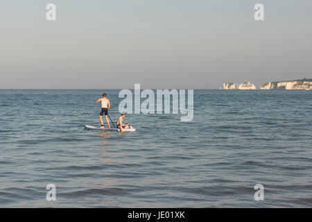 North Beach, Halbinsel Purbeck, Dorset, Großbritannien, 21. Juni 2017. Auf das, was ist, dass der letzte Tag der aktuellen Hitzewelle, ist es eine andere warme und sonnige Wetter Tag am schönen Sandstrand an der Südküste beliebt bei Urlaubern und Tagestouristen gleichermaßen. Ein Sea Breeze moderiert Temperaturen um 24 Grad, ein paar Grad niedriger als die Rekordtemperaturen im Inland erfasst. Zwei Jungen spielen auf einem Paddle Board mit Old Harry Rocks im Hintergrund. Stockfoto