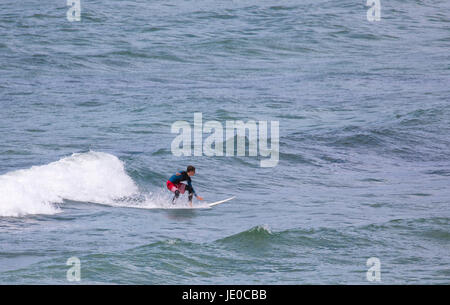 Eine einsame männliche Surfer Fang eine Welle an der beliebten und renommierten surfen Strand von Polzeath, Cornwall, England, Großbritannien Stockfoto