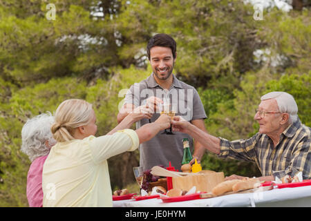 Familie Toasten einander beim Mittagessen im Picknick-Tisch im freien Stockfoto