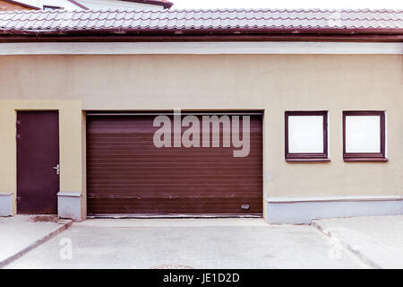 geschlossene braun gewellte Metall-Garage Tor mit Tür und zwei Fenster auf Putz Stockfoto