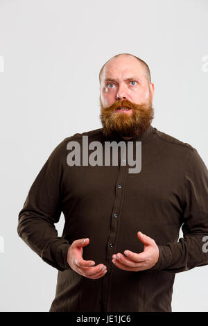 Überrascht Mann mit braunen Shirt und Schnurrbart auf leeren grauen Hintergrund, Freiraum für Inschrift Stockfoto