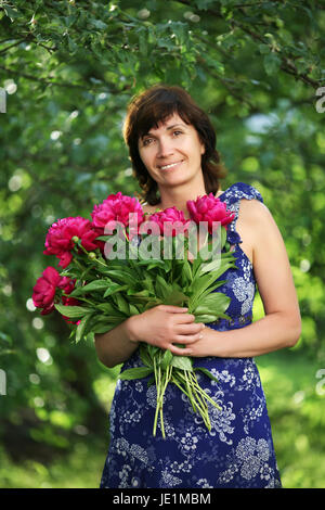 Die durchschnittliche Frau mit Blumen in einem Garten Stockfoto