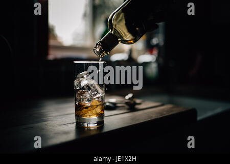 Whisky in einem Tumbler Glas gegossen wird. Alkoholische Getränke und Getränke Foto von Paulo Santos. Stockfoto