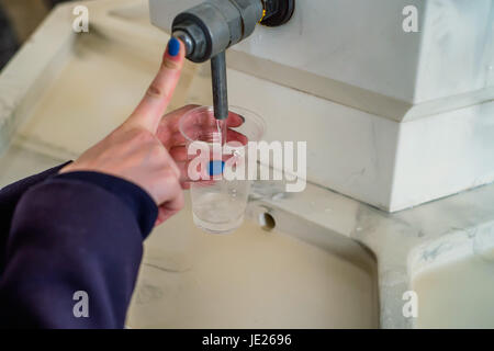 Frau schüttet Mineralwasser im Glas in der Trinkhalle Stockfoto