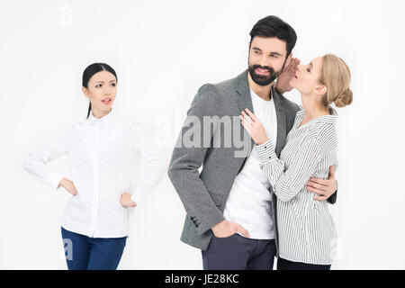 Frau, Flüstern, Mann mit eifersüchtigen Freund in der Nähe von isoliert auf weiss Stockfoto