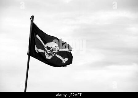 Zerfetzte Piratenflagge mit Totenkopf fliegen vom Fahnenmast - monochrome Verarbeitung Stockfoto