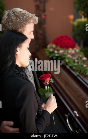 Morgen Mann und Frau auf der Beerdigung mit roter rose Stand am Sarg oder Sarg Stockfoto