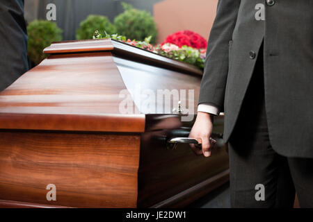 Religion, Tod und Dolor - Sarg Träger tragen die Schatulle bei Beerdigung, Friedhof Stockfoto