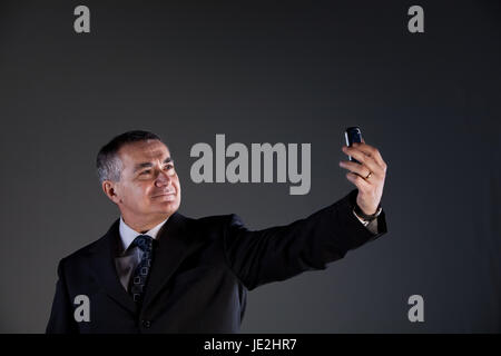 Senior Manager erfolgreich mit seinem untrennbaren Smartphone Agenda und Kalender, jetzt unter einem selfie Stockfoto