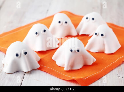 Beängstigend weißen essbare Halloween Ghost Vorspeisen für Party Snacks und Leckereien für Kleinkinder treating Allhallows Vorabend bereit auf einer bunten orange Serviette Stockfoto