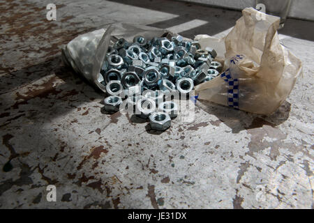 Plastikbeutel der Last der neuen Legierung Muttern über einen mechanischen Tisch Stockfoto