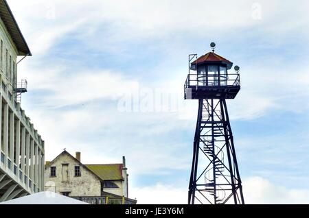 Die alte Garde Turm auf der Insel Alcatraz Gefängnis, heute ein Museum, in San Francisco, Kalifornien, USA. Ein Blick auf den Wachturm, der Kaserne, Gebäude 64 und eine Möwe fliegen. Stockfoto