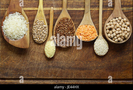 Verschiedene Arten von Getreide in hölzerne Löffel - Kichererbsen, Reis, Quinoa, Buchweizen, Linsen Stockfoto