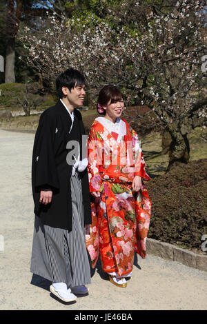 Japanische Brautpaar in bunten Hochzeits-Kimonos mit ihrem Porträt genommen im Kenrokuen Garten in Kanazawa, Japan während der Kirschblüte. Stockfoto