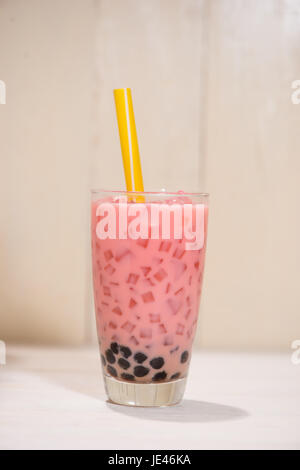 Boba / Bubble Tea. Hausgemachte Erdbeer-Milchtee mit Perlen auf Holztisch. Stockfoto