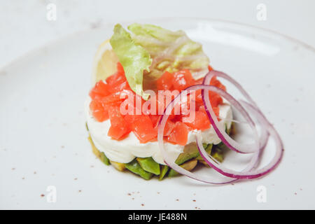 Salat mit Lachs, Avocado und Käse mit Salatblättern dekoriert. Stockfoto