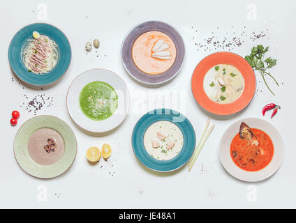 Platten mit verschiedenen Arten von Suppen auf einem weißen Tisch. Stockfoto