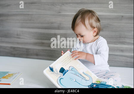 Einjähriges Kind eine bunte Kinder-Buch zu betrachten. Stockfoto