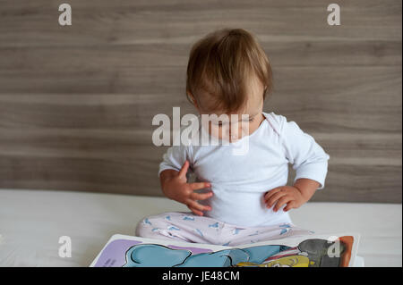 Einjähriges Kind eine bunte Kinder-Buch zu betrachten. Stockfoto