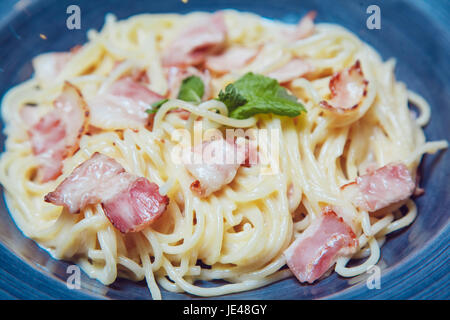 Spaghetti Carbonara mit Speck und Käse auf der blauen Platte. Stockfoto