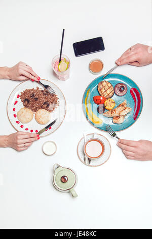 Hände eines Mannes und einer Frau an einem Tisch mit Essen. Stockfoto