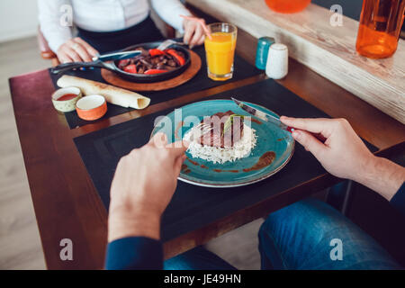 Mann und Frau sind am Tisch essen. Nur die Hände. Stockfoto