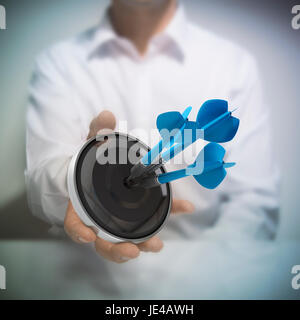 Mann hält auf schwarzen Ziel mit drei blauen Pfeilen trifft das Zentrum. Konzept-Bild zur Veranschaulichung der Marketing- und Werbe-Erfolg oder Selbstvertrauen. Stockfoto