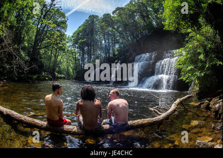 Drei Freunde genießen das Wasser beim Sgwd Y Pannwr Wasserfall in Brecon-Beacons-Nationalpark in Wales. Stockfoto