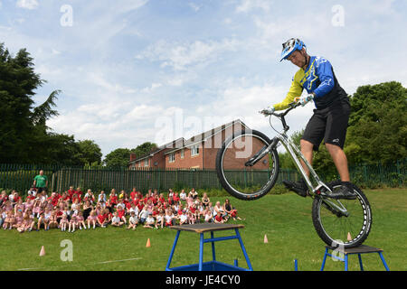 Danny Butler der Extreme Mountain Bike Show einen Stunt für Kinder in einer Schule durchführen. Stockfoto