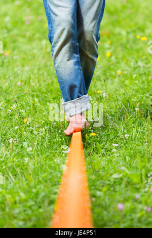 Guy üben Slackline im Stadtpark. Slacklinen ist eine Praxis in der Balance, die in der Regel, Nylon oder Polyester Gurtband zwischen zwei Ankerpunkten gespannt verwendet. Stockfoto