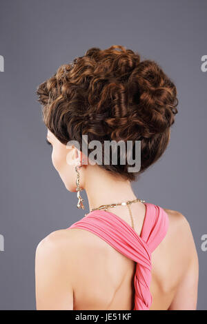 Krauses Haar. Rückansicht des braunen Haaren Frau mit festlichen Frisur Stockfoto