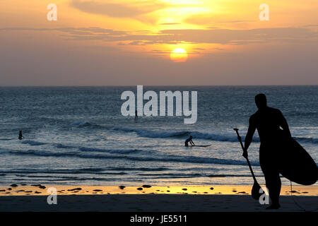 Silhouette der Surfer Board während des Sonnenuntergangs auf der Backgrounf Od Swa paddeln wo gibt es eine andere Surfer im Wasser Stockfoto