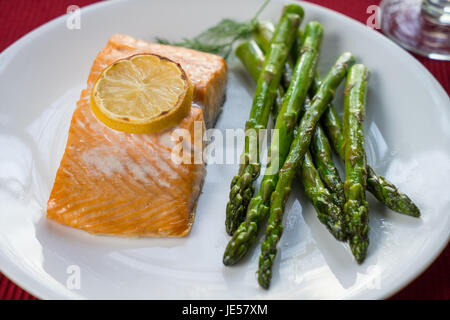 Gegrillter Lachs und Zitrone auf einem weißen Teller mit Spargel Stockfoto