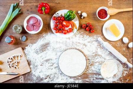 Draufsicht der verschiedenen Pizza-Zutaten und Gemüse Teig auf hölzernen Tischplatte Stockfoto