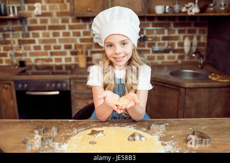 Mädchen hält rohe Herz geformten Teig für cookie Stockfoto