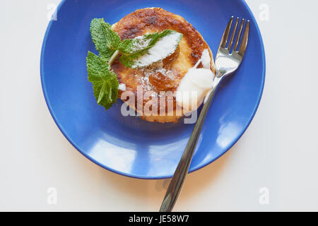 Bescheidenes Frühstück gesunden Menschen. Pfannkuchen aus Quark Quark mit Rosinen, saurer Sahne und Minze-Zweig Stockfoto