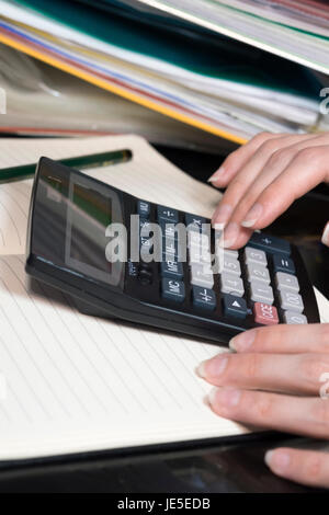 Hände, Notebook, grünen Stift und Taschenrechner liegen auf dem Tisch Stockfoto