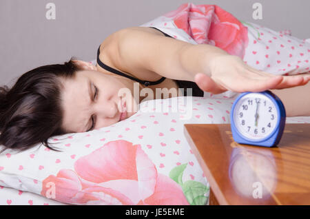 Frau schlafend im Bett, neben einen Wecker auf dem Tisch, die Plätze an den 06:00 Stockfoto