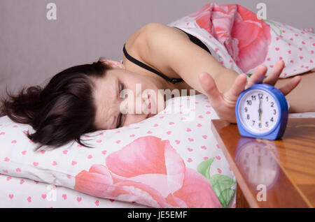 Frau schlafend im Bett, neben einen Wecker auf dem Tisch, die Plätze an den 06:00 Stockfoto