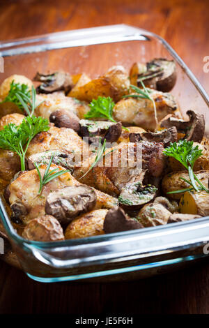 Lecker gebackene Hähnchenschenkel mit Kartoffeln, Pilzen und Kräutern Stockfoto