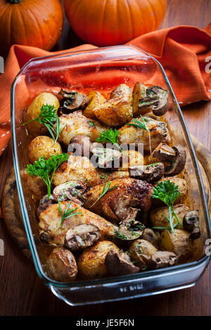 Lecker gebackene Hähnchenschenkel mit Kartoffeln, Pilzen und Kräutern Stockfoto