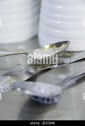 Teelöffel mit Seifenblasen und weiße Tassen auf Abtropffläche aus Edelstahl. Stockfoto