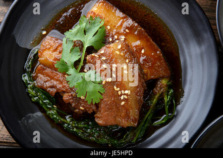 Chinesische süß gedünstet Schwein Einstellung auf schwarzen japanischen Stil Teller in Studiobeleuchtung. Stockfoto