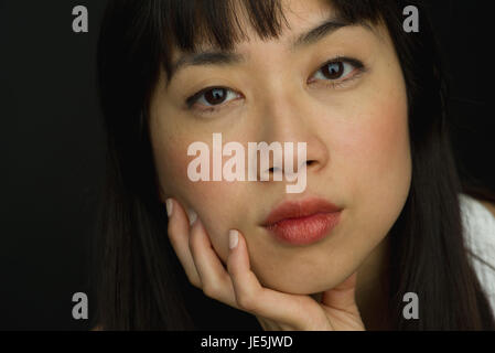 Junge Frau mit der Hand unter Kinn, close-up portrait Stockfoto