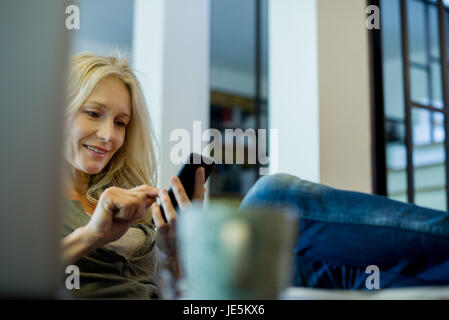 Reife Frau entspannend mit smartphone Stockfoto